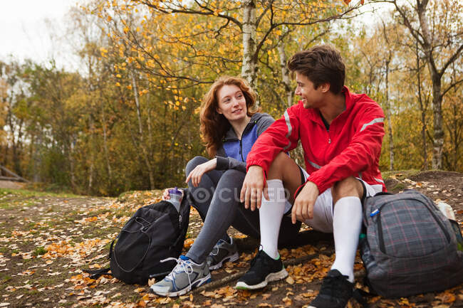 Молода пара в спортивному одязі сидить у лісі — стокове фото
