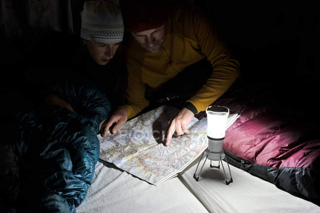 Pareja en sacos de dormir, mirando el mapa del sendero, Yak Kharka, Nepal - foto de stock