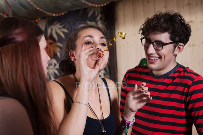 Young blowing streamer with friends — Stock Photo