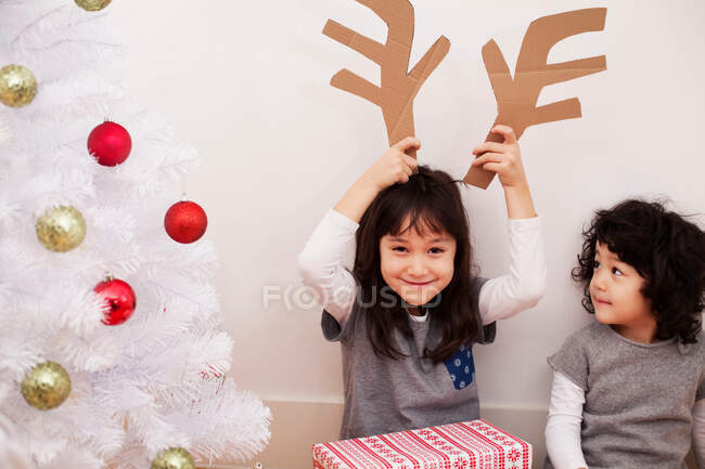 Дві дівчини готуються до Різдва, граючи з картонними оленями — стокове фото