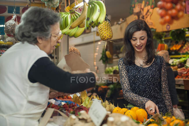 Femme faisant du shopping chez le marchand de légumes au marché — Photo de stock