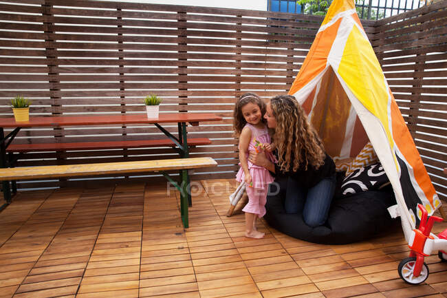 Mother and daughter by tent on patio — Stock Photo