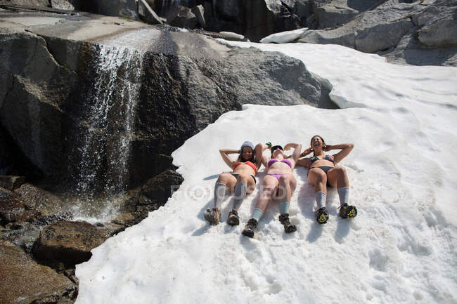 Tre giovani donne in bikini, sdraiate sulla neve, The Enchantments, Alpine Lakes Wilderness, Washington, USA — Foto stock