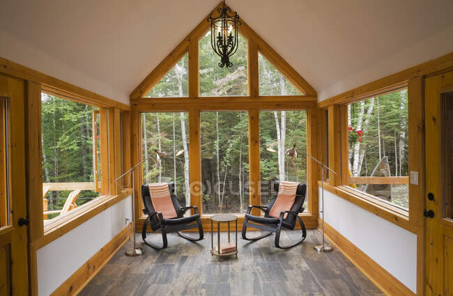 Sala de leitura com piso de cerâmica e duas cadeiras de balanço de couro preto dentro de uma cabine de madeira de estilo cottage, Quebec, Canadá. Esta imagem é propriedade liberada. CUPR0291 — Fotografia de Stock