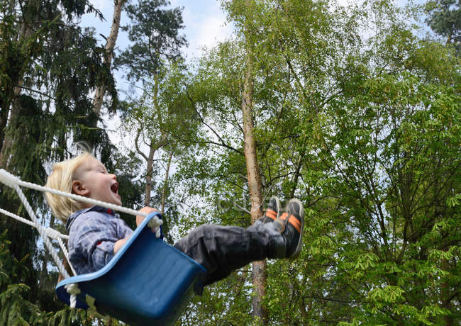 Happy Boy swinging on playground — Stock Photo