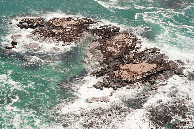 Скалы с волнами для серфинга в лазурной морской воде — стоковое фото
