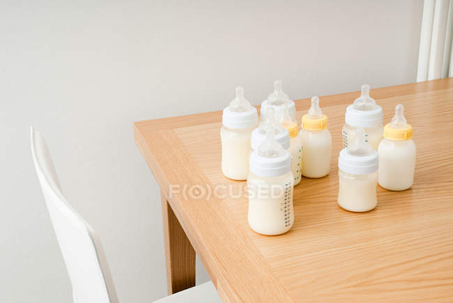 Botellas de leche para bebés colocadas en la mesa - foto de stock