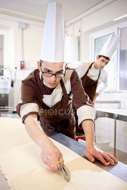Bäcker schneidet Teig in Küche — Stockfoto