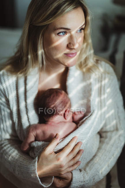 Portrait of adult woman cradling new born baby daughter wrapped in cardigan — Stock Photo