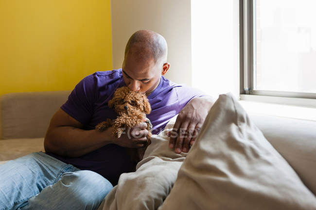 Mid adulto macho sentado no sofá com cão — Fotografia de Stock