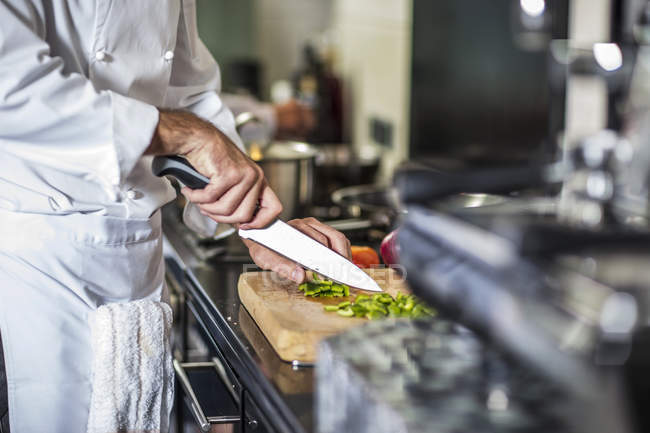 Шеф-кухар подрібнює зелений перець на дошці — стокове фото