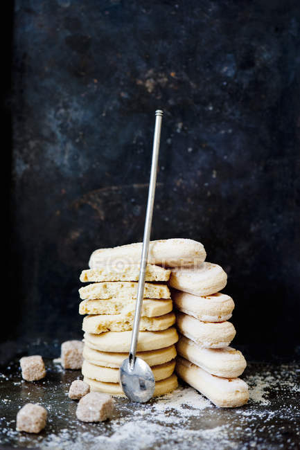 Stack of biscuits and spoon on tabletop on black background — Stock Photo