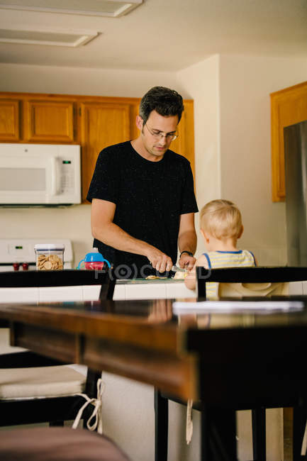 Padre e hijo pequeño en casa, padre preparando comida - foto de stock