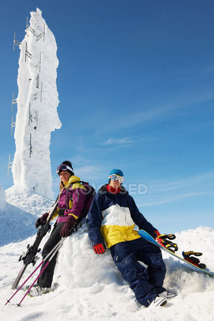 Snowboarder and skier at the top of mountain with equipment, in front of ice sculpture — Stock Photo