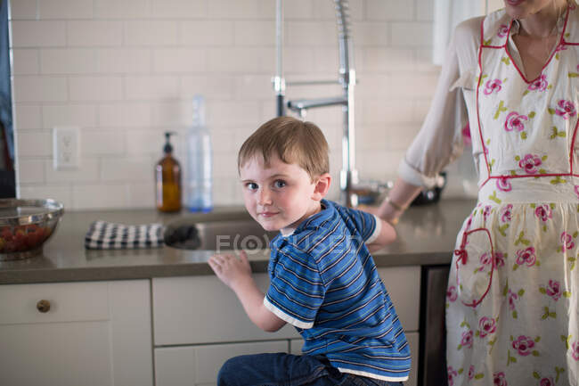 Menino na pia da cozinha olhando por cima do ombro — Fotografia de Stock