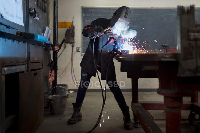 Soldadura de trabajadora metalúrgica en el banco de trabajo del aula - foto de stock