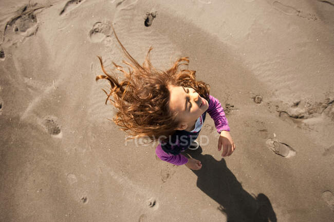 Молодий грає на піщаному пляжі, зверху — стокове фото