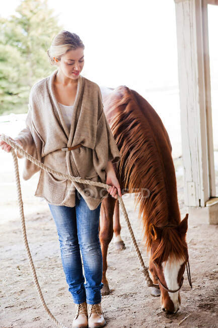 Молода жінка доглядає за конем на фермі — стокове фото