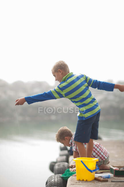 Два хлопчики ловлять рибу на пірсі. — стокове фото