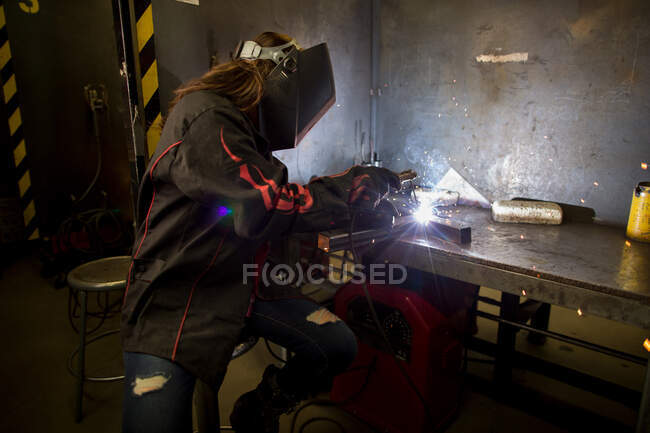 Female metalsmith welding metal at workbench — Stock Photo