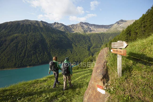 Rear view of young couple hiking at Vernagt reservoir, Val Senales, South Tyrol, Italy — Stock Photo