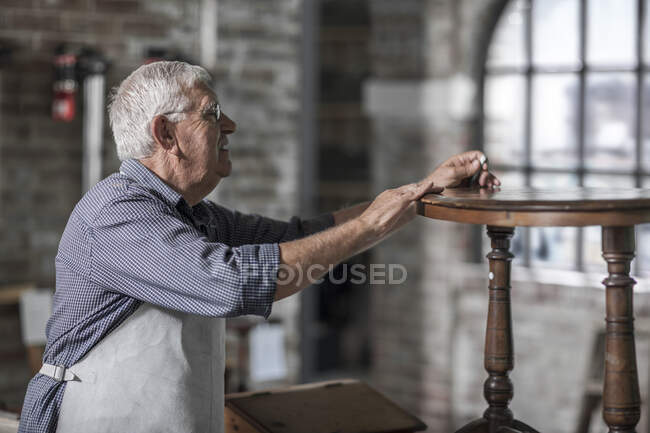 Кейптаун, Южная Африка, пожилой ремесленник, работающий на деревянном столе в мастерской — стоковое фото