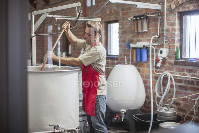 Cape Town, South Africa, young male stirring beer in brewery room — Stock Photo