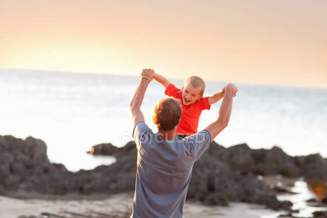 Padre jugando con hijo en playa - foto de stock