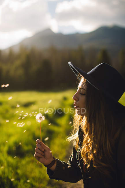 Woman blowing dandelion seeds, Rocky Mountain National Park, Colorado, USA — Stock Photo