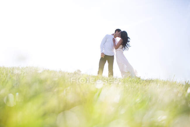 Романтична пара цілується на трав'янистому пагорбі — стокове фото