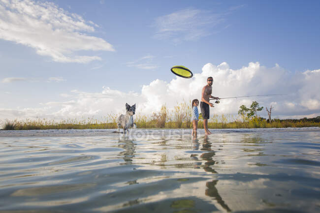Dad and daughter fishing and throwing flying disc for dog, Fort Walton Beach, Florida, USA — Stock Photo