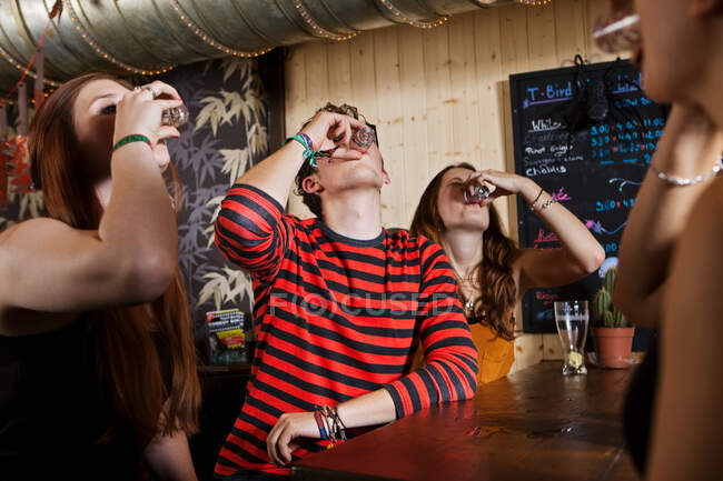 Jovens amigos bebendo de vidro de tiro no bar — Fotografia de Stock