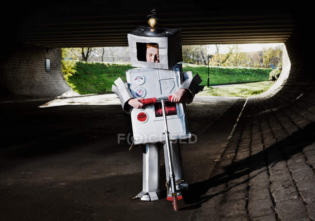 Ragazzo vestito da robot guida scooter all'aperto — Foto stock
