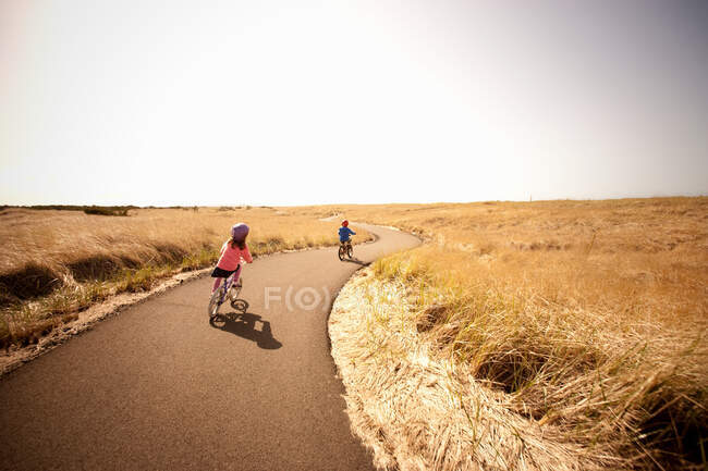 Двоє дітей катаються на велосипеді вздовж провулку — стокове фото