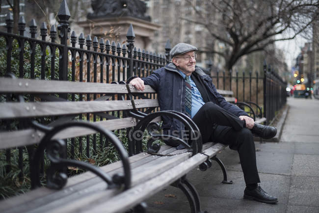 Человек, сидящий на скамейке в парке улыбается, Манхэттен, Нью-Йорк, США — стоковое фото