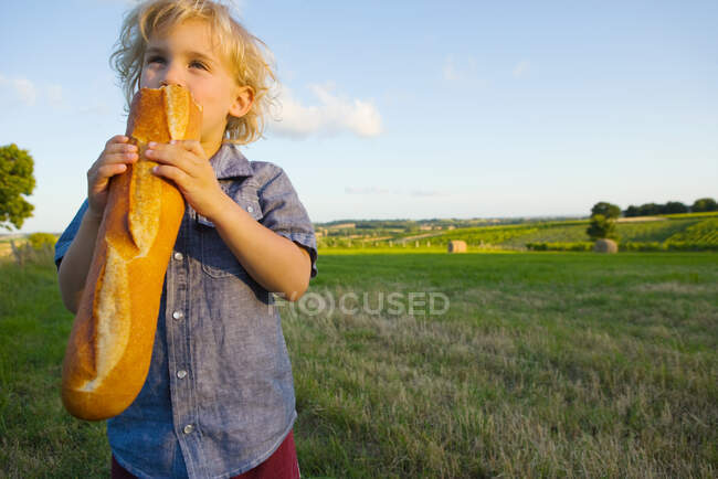 Un garçon qui mange une baguette — Photo de stock