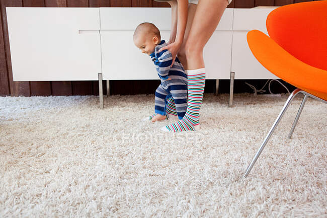 Мати допомагає малому синові робити перші кроки. — стокове фото