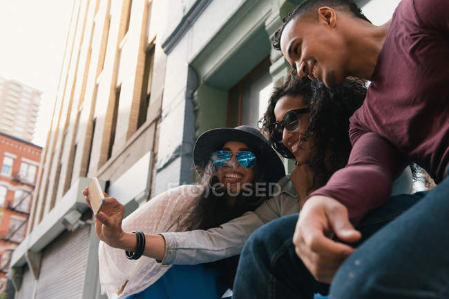 Tres amigos adultos medios posando para selfie smartphone en la calle de la ciudad - foto de stock