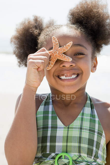 Chica sosteniendo una estrella de mar - foto de stock