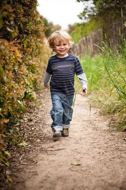 Мальчик идет по грунтовой дороге — стоковое фото