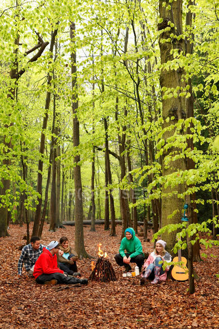Friends sitting around campfire together — Stock Photo