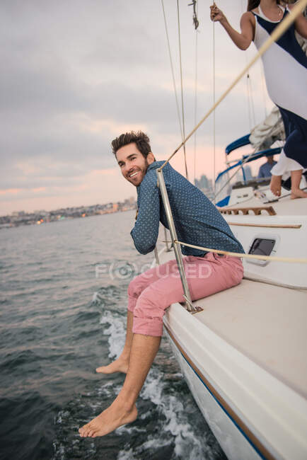 Hombre adulto sentado en la cubierta del barco - foto de stock