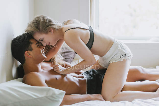 Fidanzata seduta sul fidanzato sul letto — Foto stock