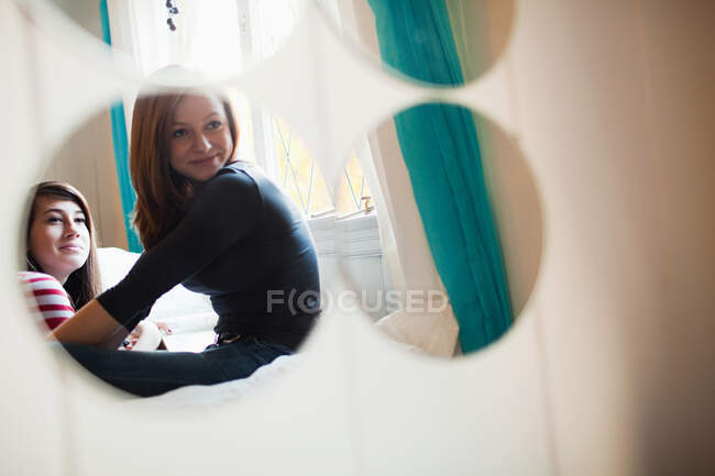 Dos chicas adolescentes hablando reflejadas en el espejo del dormitorio - foto de stock