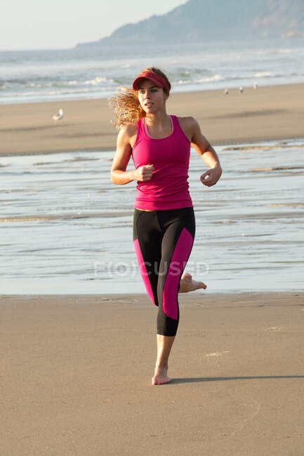 Jeune femme courant sur la plage — Photo de stock