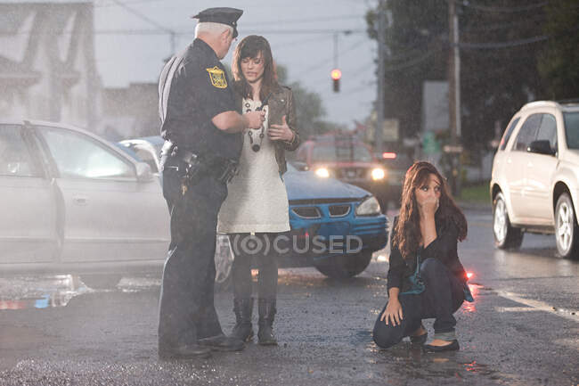 Oficial de policía y mujeres jóvenes en el lugar del accidente - foto de stock