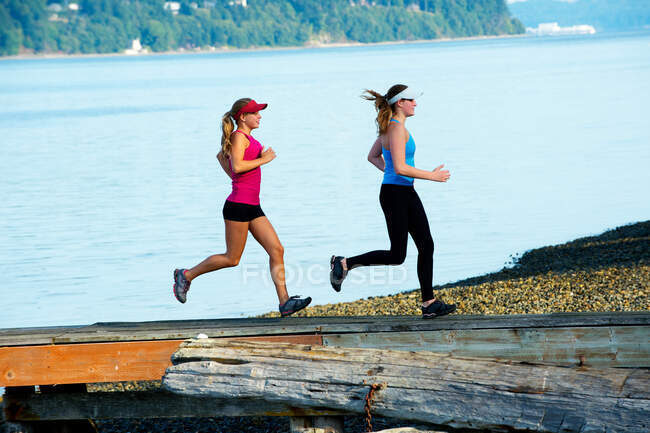 Teenage girls running together on beach — Stock Photo