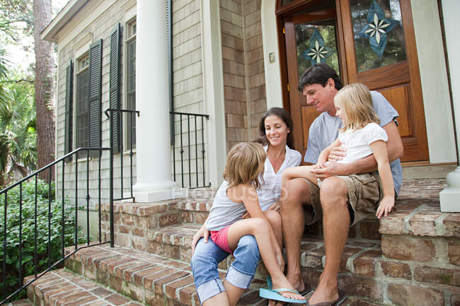 Family sitting on house steps — Stock Photo