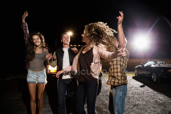 Four friends in parking lot at night — Stock Photo