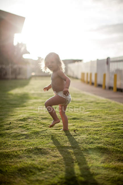 Молодий хлопчик біжить на траві, дивиться через плече, посміхається — стокове фото